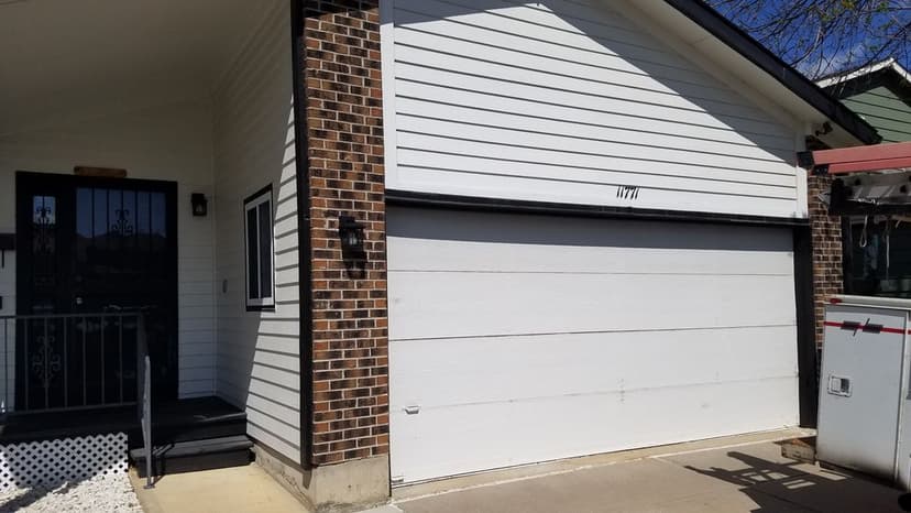 Modern house exterior with a white garage door and brick accents, featuring a black front door.